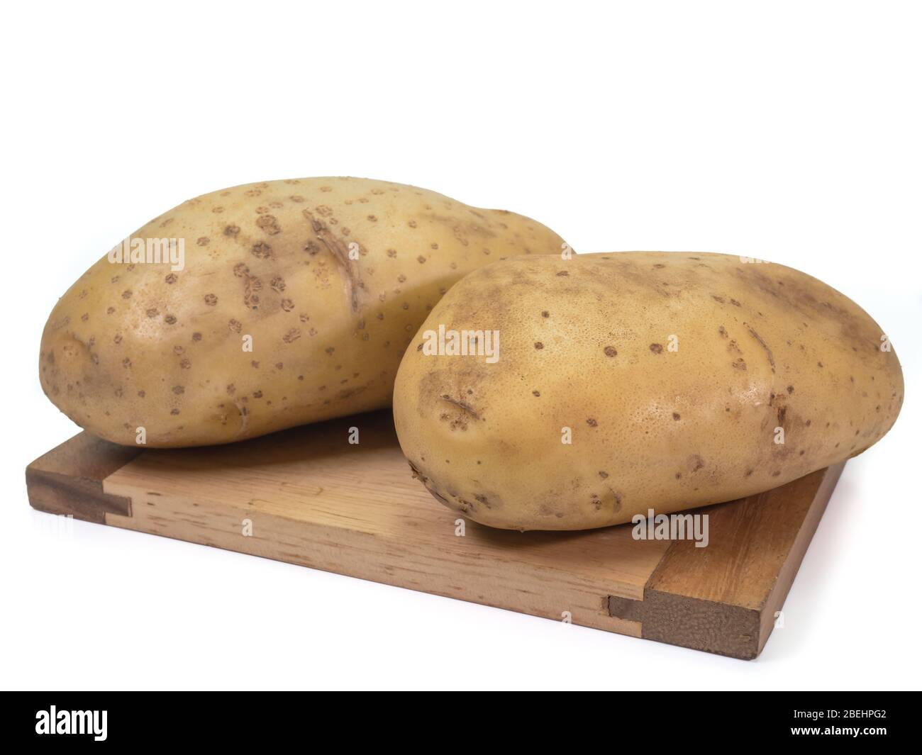 La vue rapprochée des légumes de pommes de terre biologiques frais sur un petit panneau en bois sur fond blanc. Banque D'Images