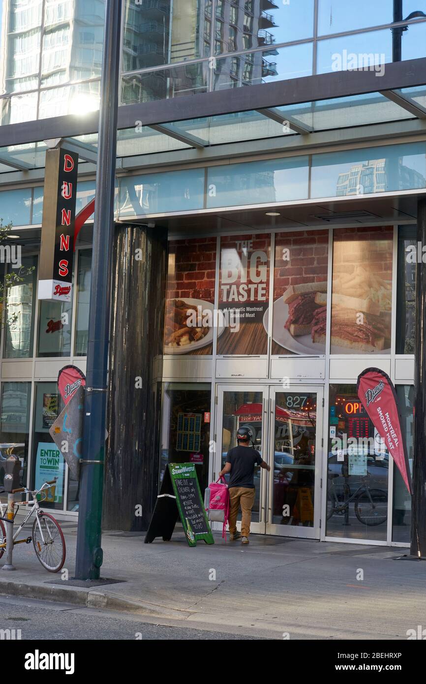 Vancouver, Canada, 11 avril 2020. Un préposé à la livraison de nourriture à domicile entre au restaurant Dunns du centre-ville de Vancouver pour prendre une commande pendant la pandémie de COVD-19. Banque D'Images