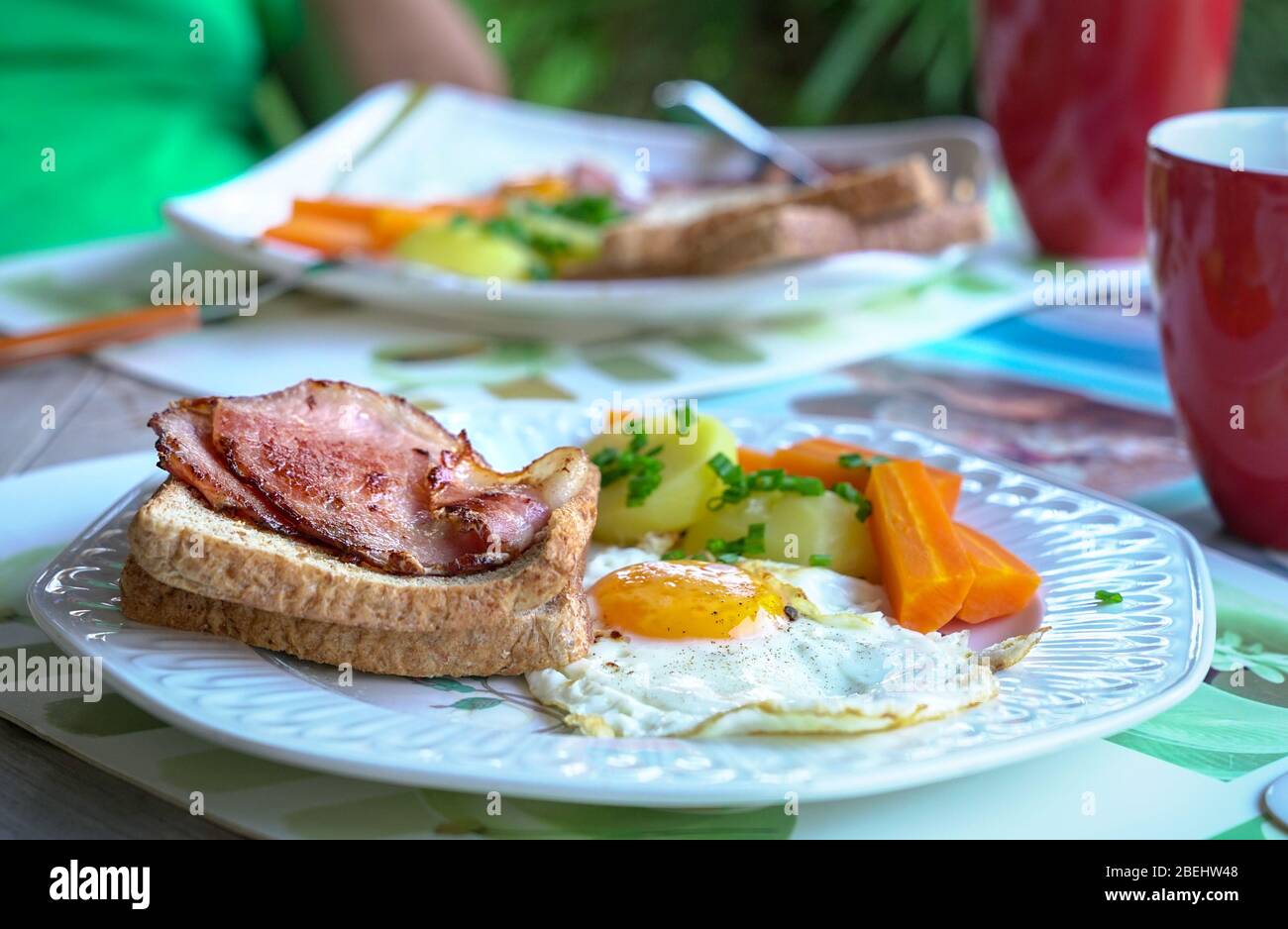Petit déjeuner avec bacon, œufs, pommes de terre, carottes et pain. Réglage de la position d'accueil. Vue latérale. Banque D'Images
