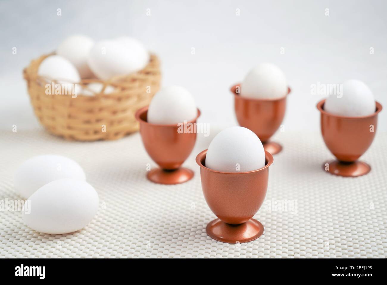 Un oeuf dans une tasse d'œufs cooper et trois autres tasses d'œufs cooper  avec un oeuf chacun et un panier avec des œufs au fond Photo Stock - Alamy