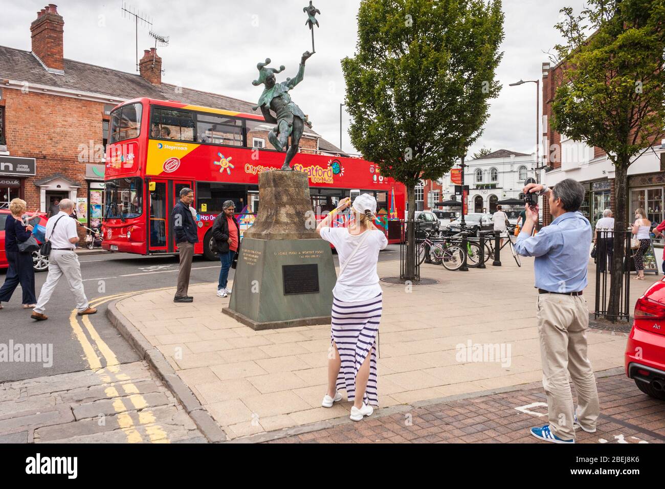 Les touristes prennent des photos de la statue de Jester comme des passes de bus pour la visite de la ville. Stratfor-upon-Avon, Warwickshire, Angleterre, GB, Royaume-Uni Banque D'Images