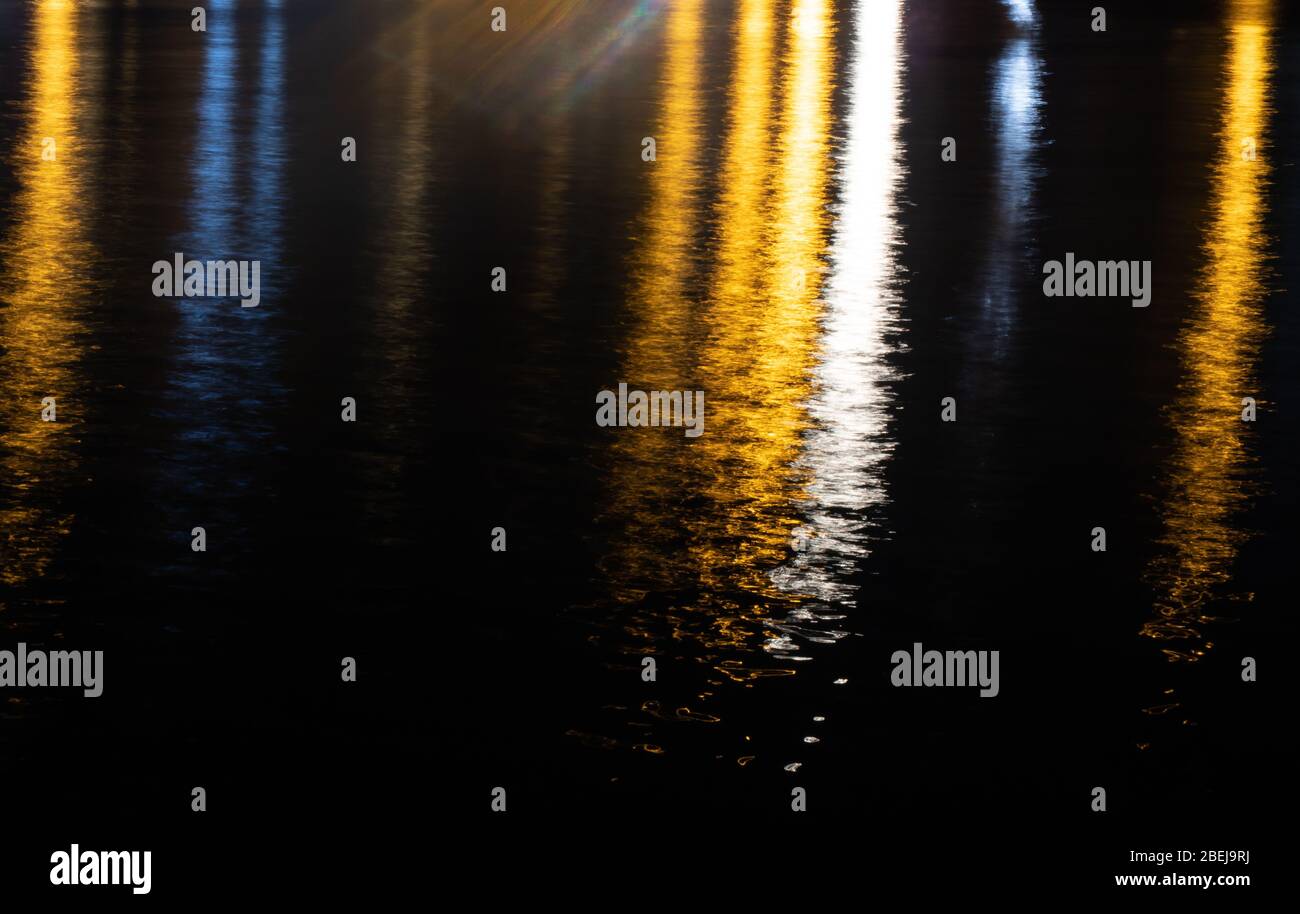 Réflexion lumineuse colorée sur la surface de l'eau. Vagues d'eau de mer la nuit. Texture de fond. Banque D'Images