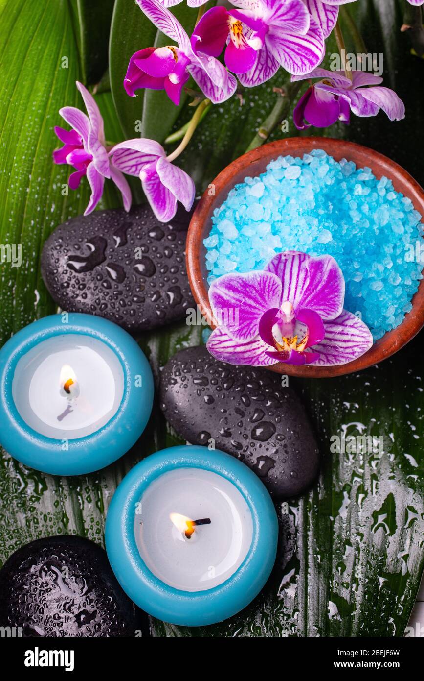 bol avec sel de bain parfumé à la lavande, orchidée, pierres de massage,  recouvert de gouttes d'eau et bougies parfumées Photo Stock - Alamy