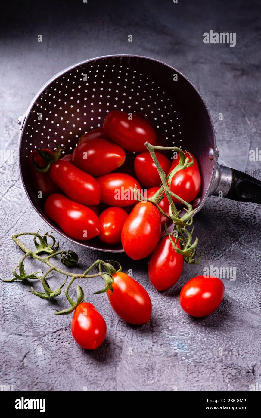 tomates fraîches et mûres dans la vieille passoire sur un fond rustique gris Banque D'Images