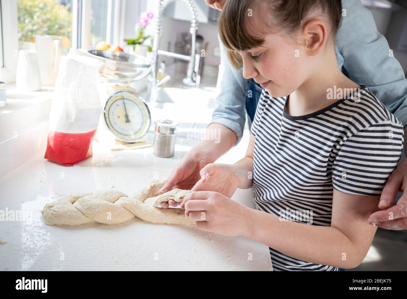 Mère et fille ayant plaisir dans la cuisine à la pâte à tresser pour le pain maison cuit ensemble Banque D'Images