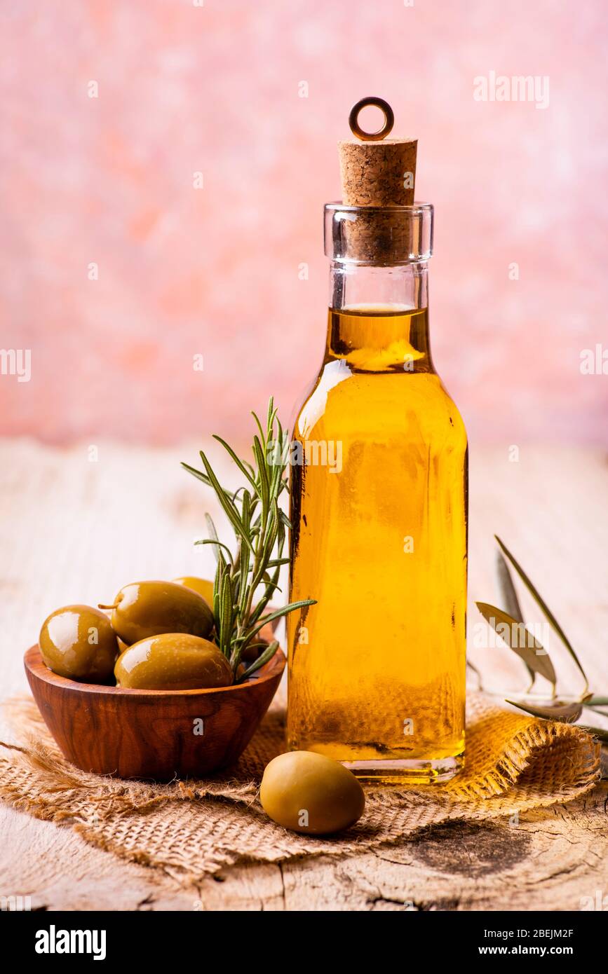 sur la table rustique en bois, bouteille d'huile d'olive extra vierge et des olives au romarin dans le bol en bois Banque D'Images