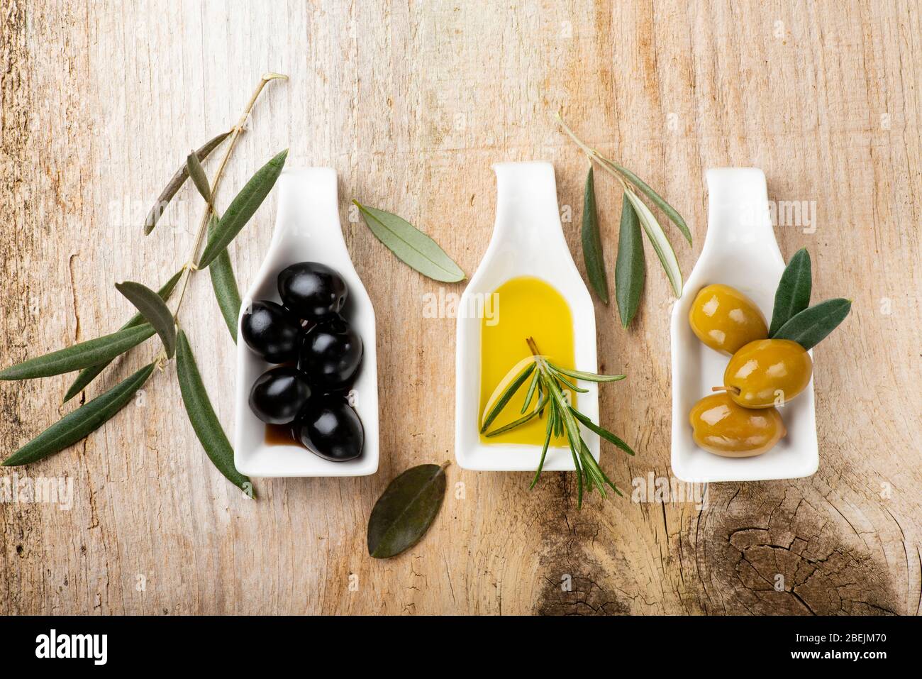 au premier plan, sur la table rustique en bois, quelques bols en céramique blancs avec des olives vertes et noires et de l'huile d'olive extra vierge. Banque D'Images
