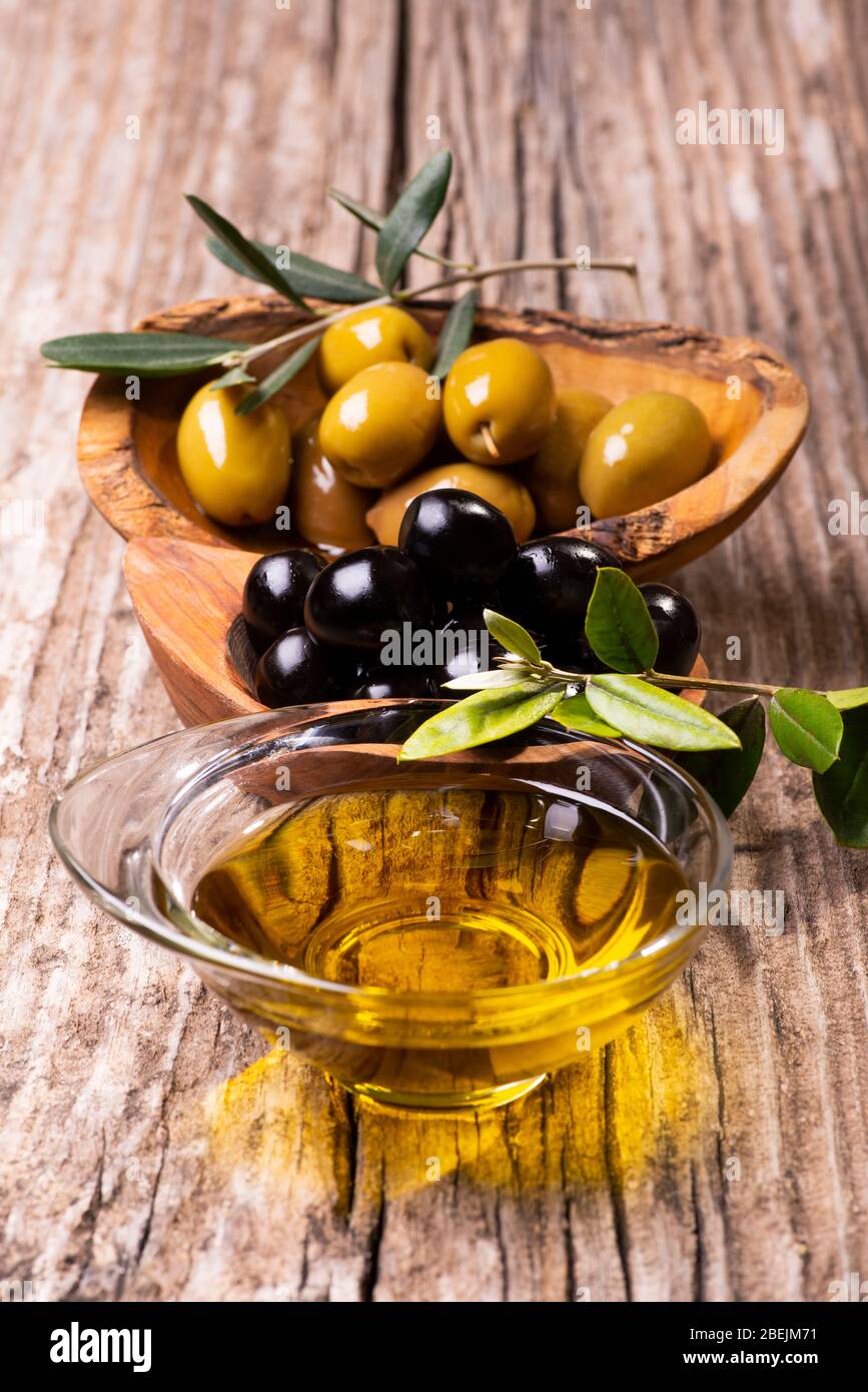 mise au point sélective. Sur la table rustique en bois, bols avec olives, branche olive et huile d'olive extra vierge Banque D'Images