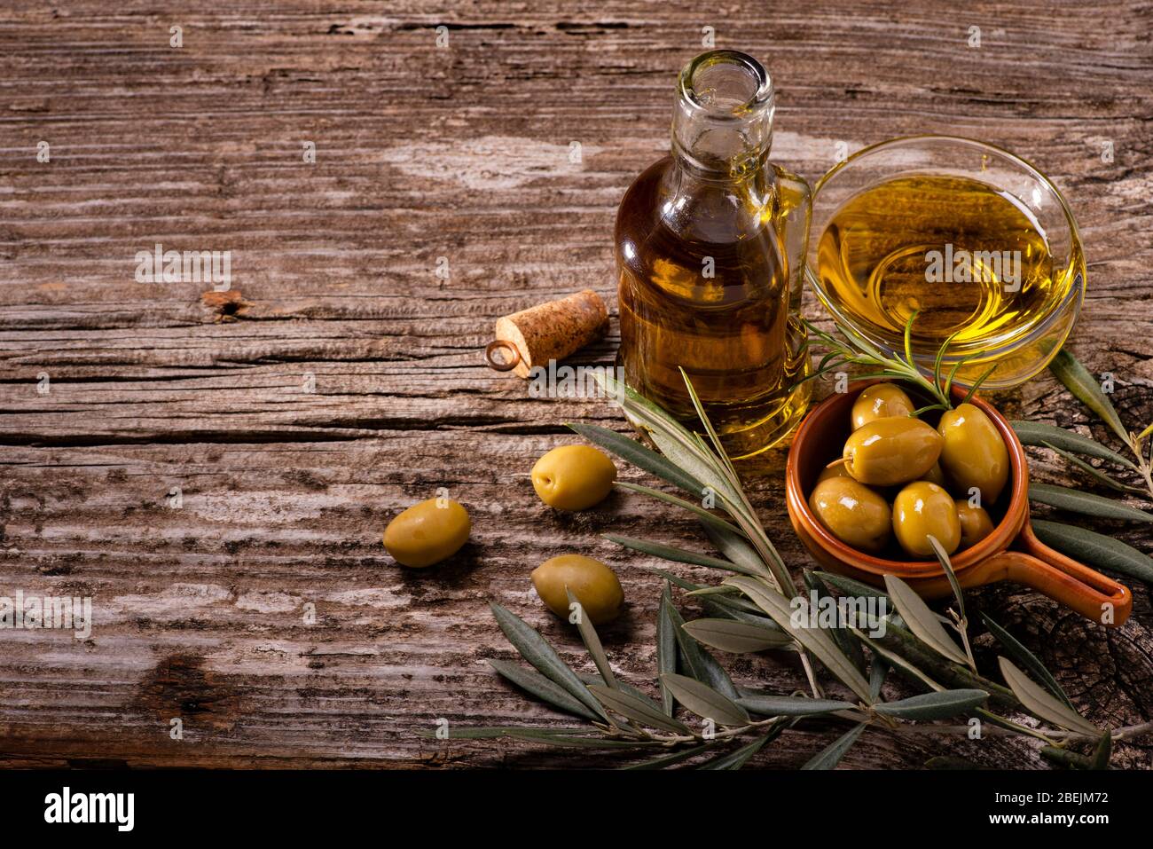 au premier plan, sur la table rustique en bois, bols aux olives vertes, branche olive et huile d'olive extra vierge Banque D'Images