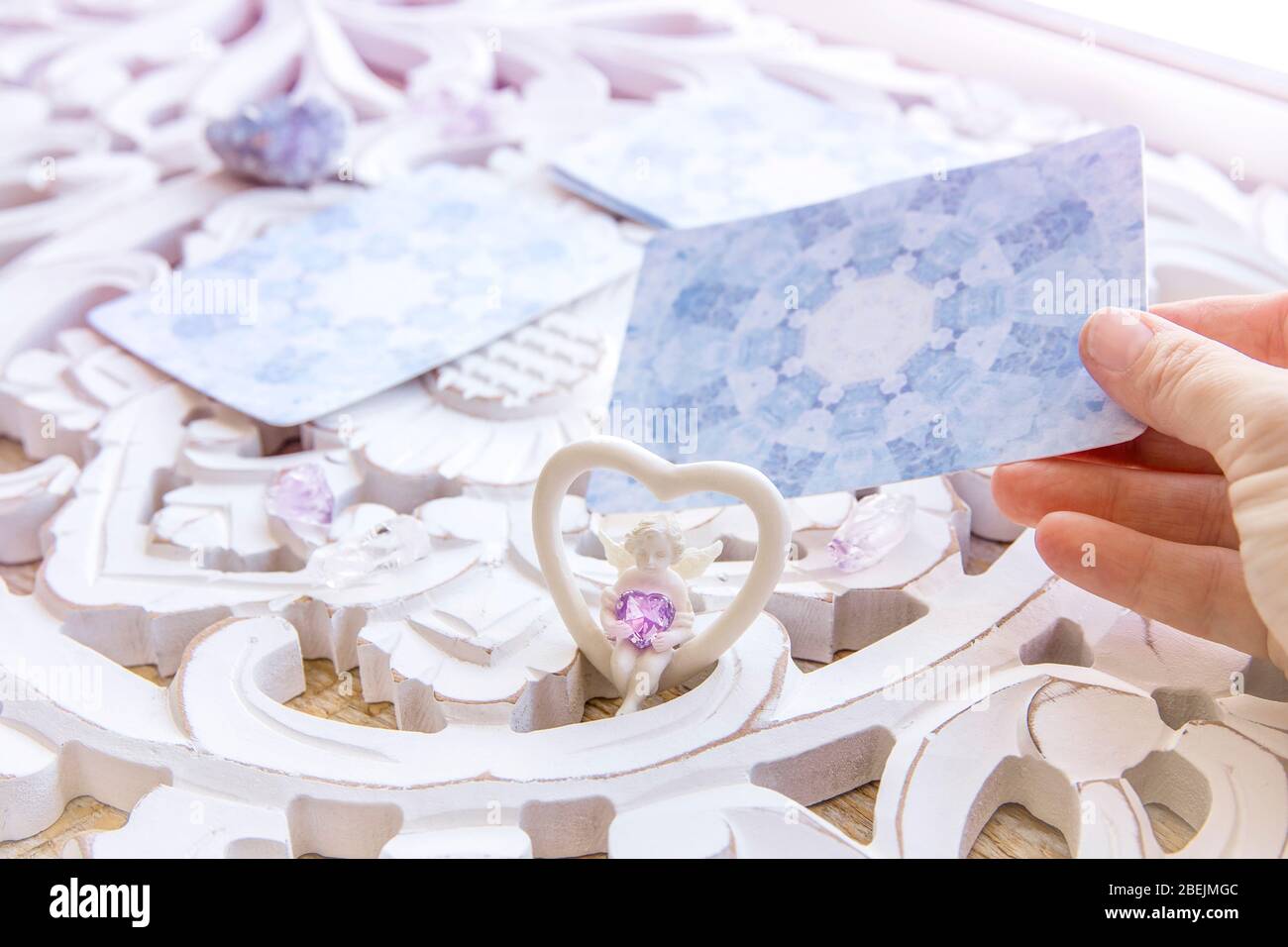 Terrasse avec divination faite maison cartes d'ange sur une table blanche vive, entourée de cristaux de pierres semi-précieuses et de bougies. Mise au point sélective sur un joli an Banque D'Images