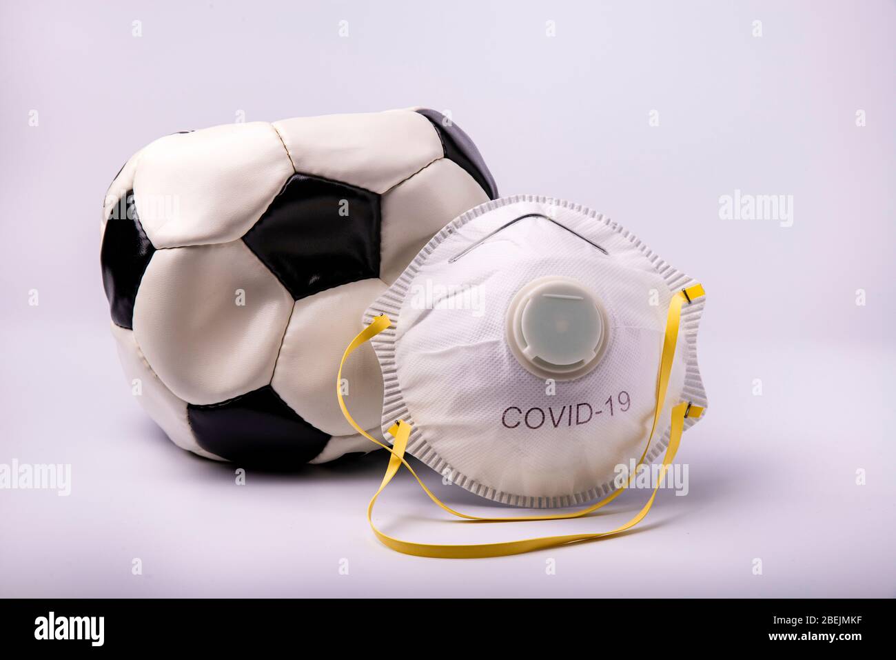 Au premier plan, un masque de protection et un ballon de football dégonflé  symbolisent la suspension du terrain de football en Italie et en Europe  comme une méa préventive Photo Stock -