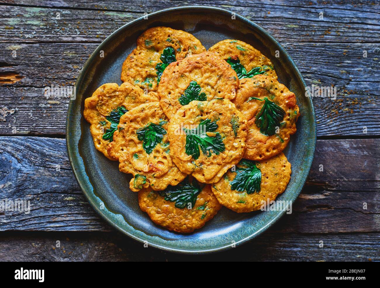 Crêpes aux pois chiches indiens végétaliens, légumes et persil, en forme de plaque vue du dessus Banque D'Images