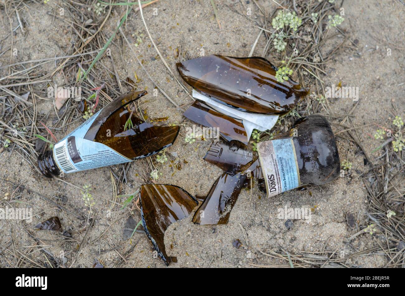 Odessa, Ukraine - 9 avril 2020: Bouteille de bière cassée dans le sable. Une bouteille de bière légère Robert Doms après la fête en plein air. Vue de dessus. Sélection Banque D'Images