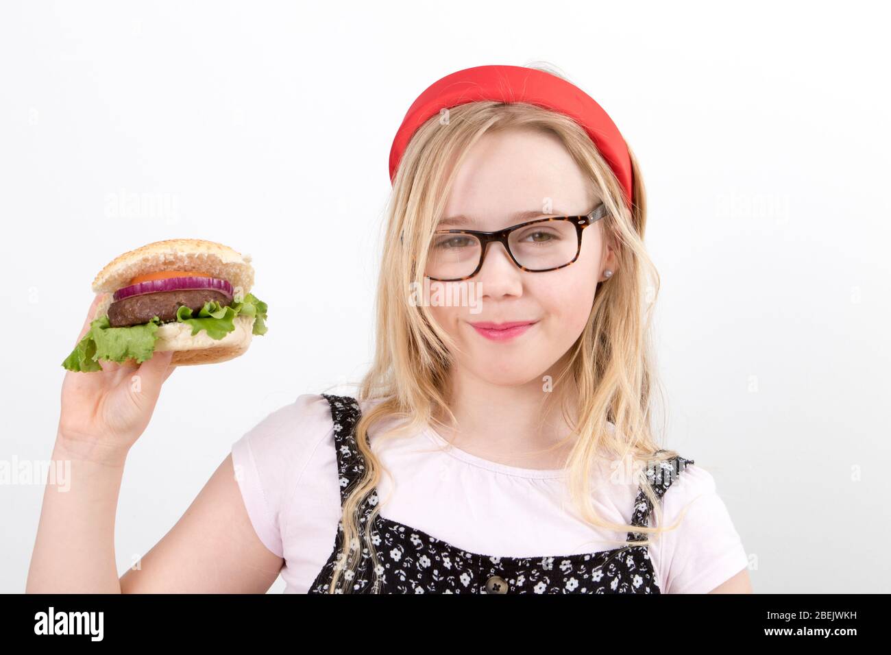 Une jeune fille blonde porte des lunettes dans un groupe rouge Alice qui tient un hamburger maison Banque D'Images