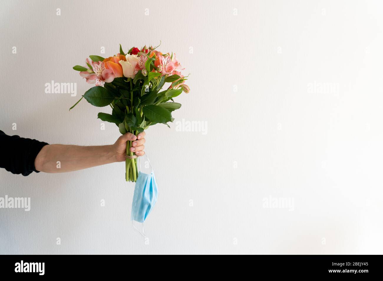 Bouquet de fleurs et masque de protection à la main masculine Banque D'Images