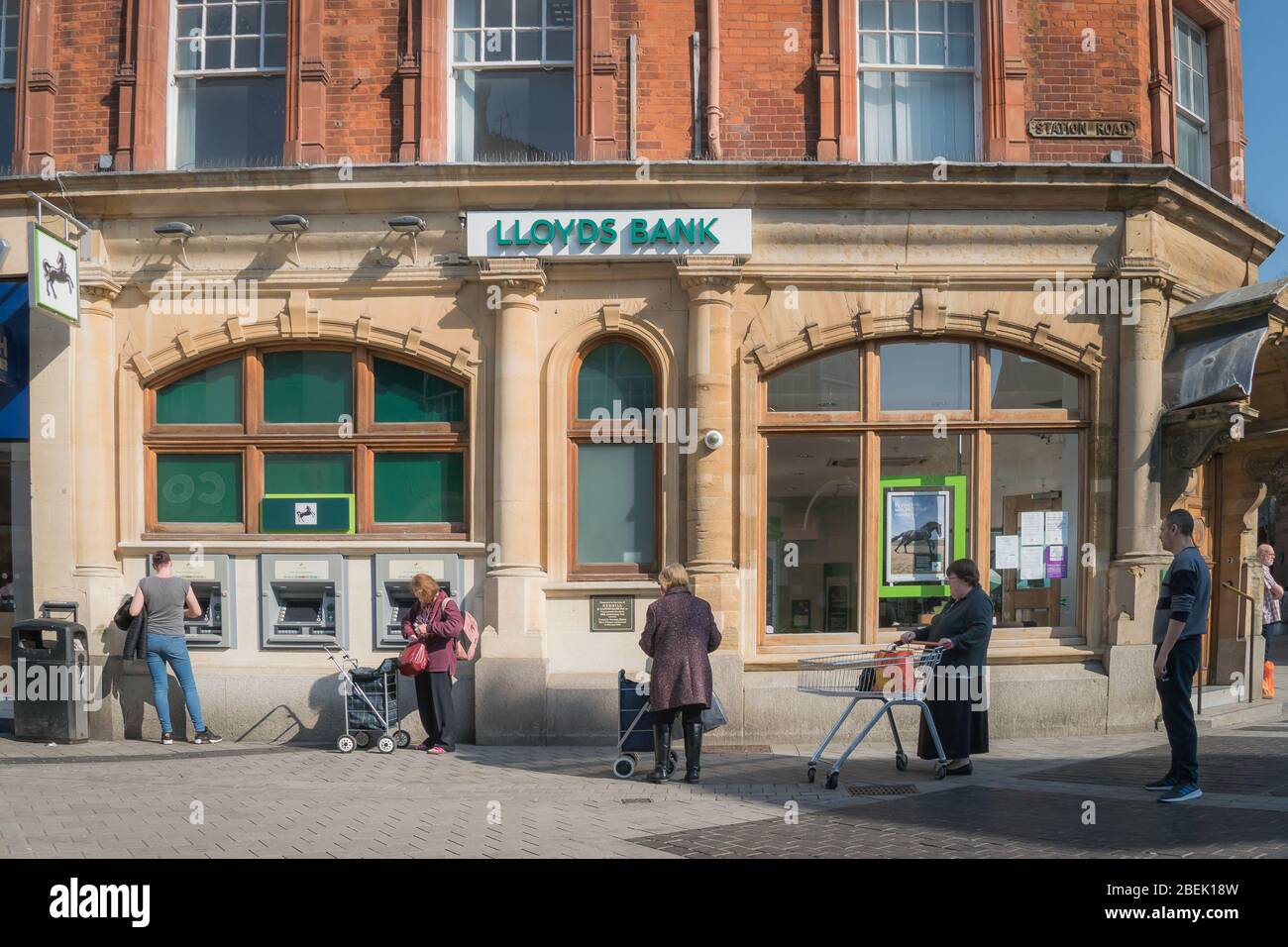 Redhill, Surrey, Royaume-Uni - 10 avril 2020 - des gens font la queue à une machine à billets, maintenant des distanciation sociale pour arrêter la propagation du coronovirus Banque D'Images