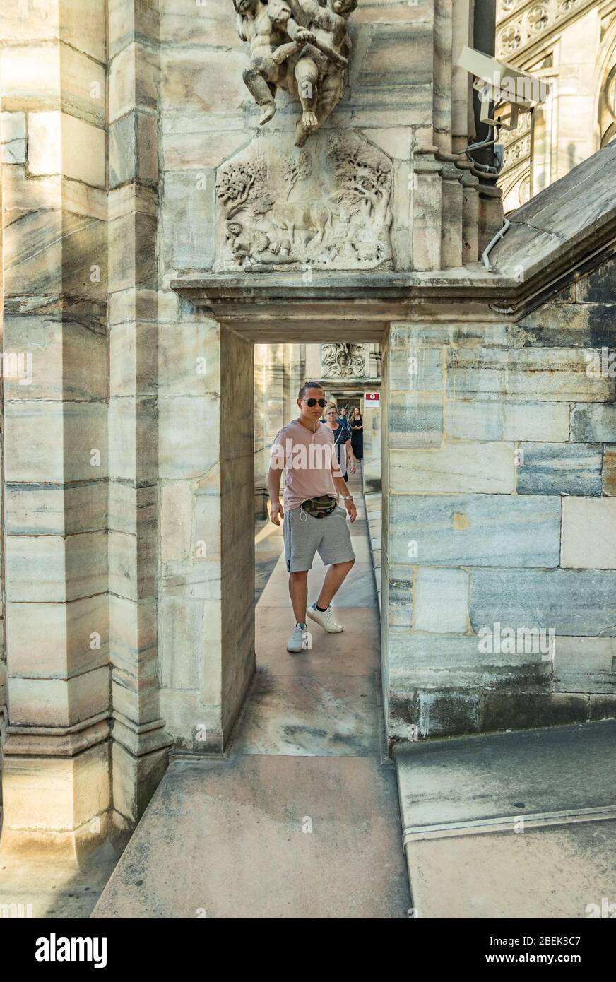 Milan, Italie - 1 août 2019. Un jeune homme en lunettes de soleil avec un sac sur sa ceinture se tient sur le toit de la cathédrale de Milan en Italie. Portrait de mise au point sélective. Banque D'Images