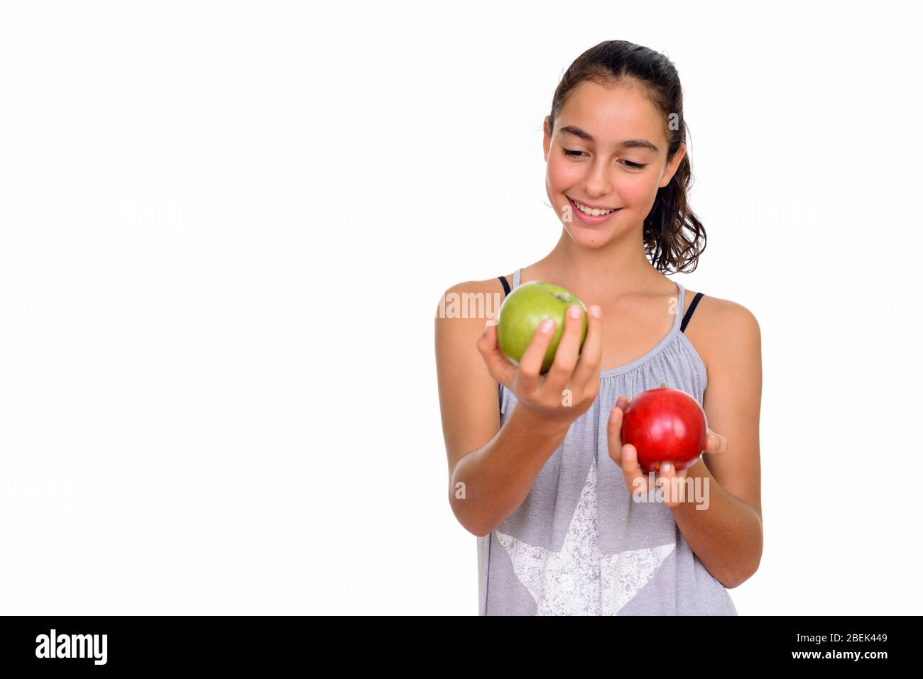 Studio tourné de jeune adolescente heureuse tenant la pomme verte et rouge Banque D'Images