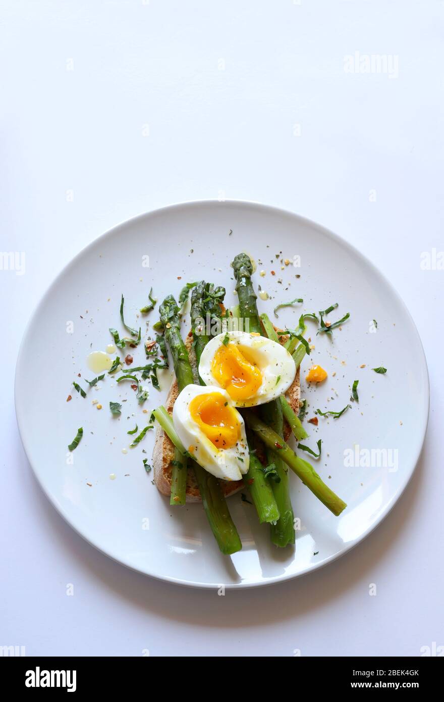 Concept de la nourriture du petit déjeuner.délicieux toast avec asperges, œufs pochés et épices servis sur plaque sur fond blanc. Vue de dessus, espace de copie. Une nourriture saine. Banque D'Images