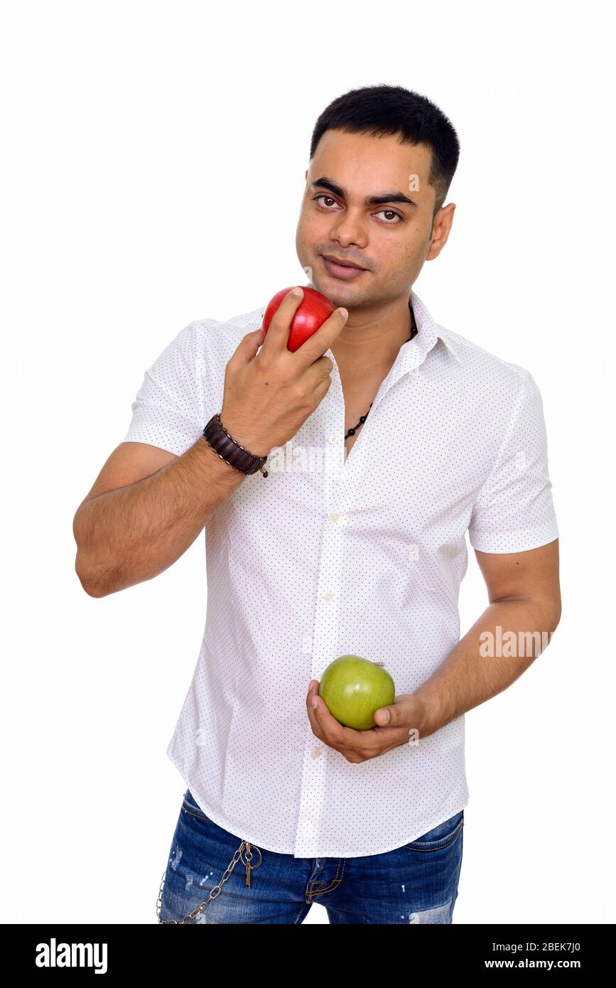 Studio tourné de jeune homme indien portant une pomme rouge et verte isolée sur fond blanc Banque D'Images