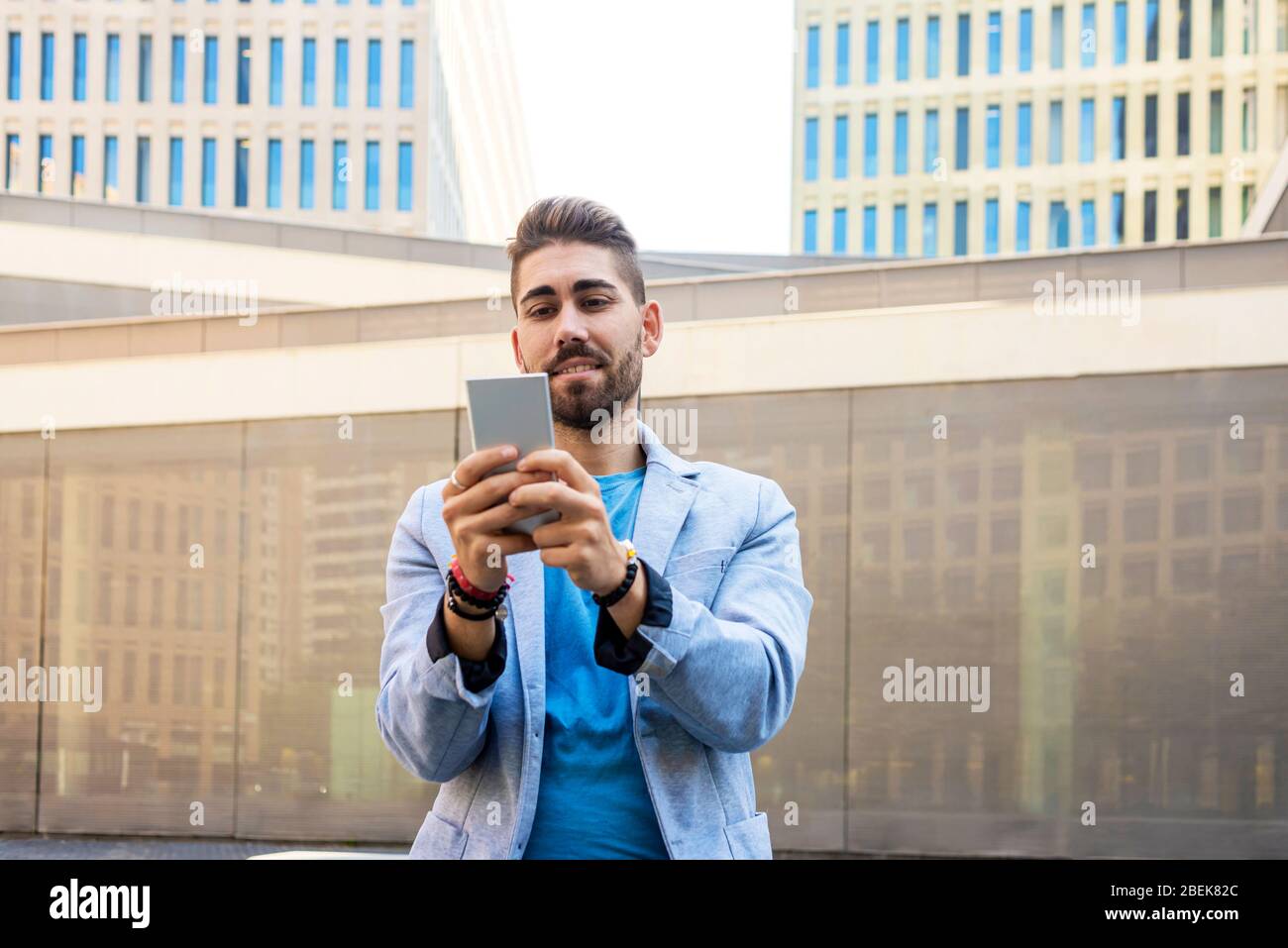 Portrait de beau jeune homme souriant quand il utilise son téléphone mobile Banque D'Images