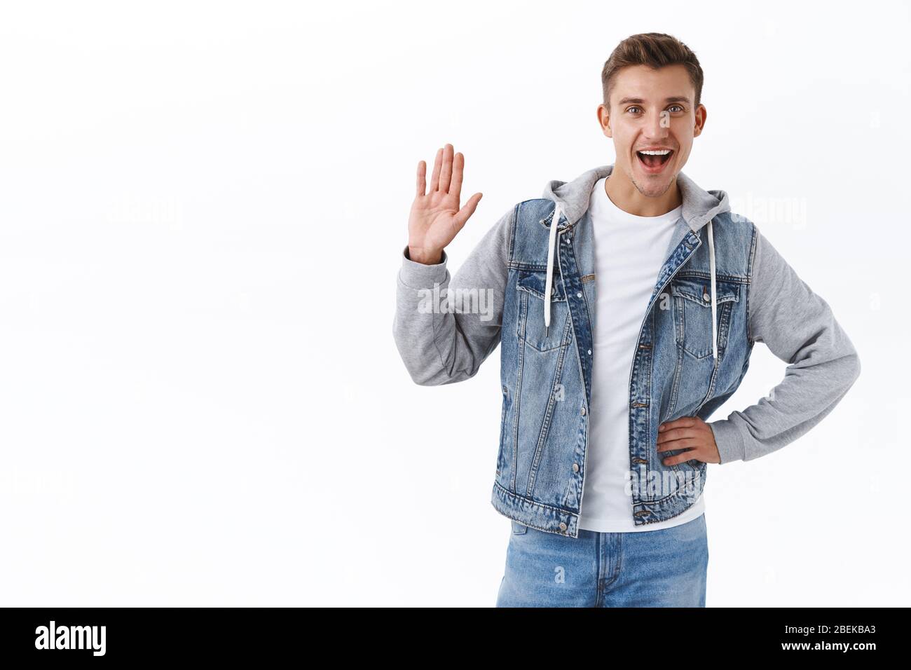 Portrait de sympathique homme blond caucasien, en se lasant la main pour dire hi, souriant largement, montrant bonjour, geste de voeux, personne de bienvenue, dire Banque D'Images