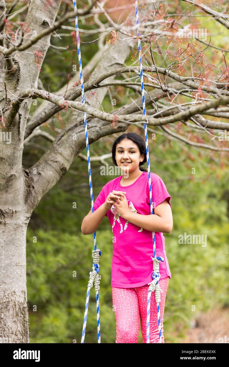 Portrait extérieur d'une jeune fille sur un swing au printemps Banque D'Images