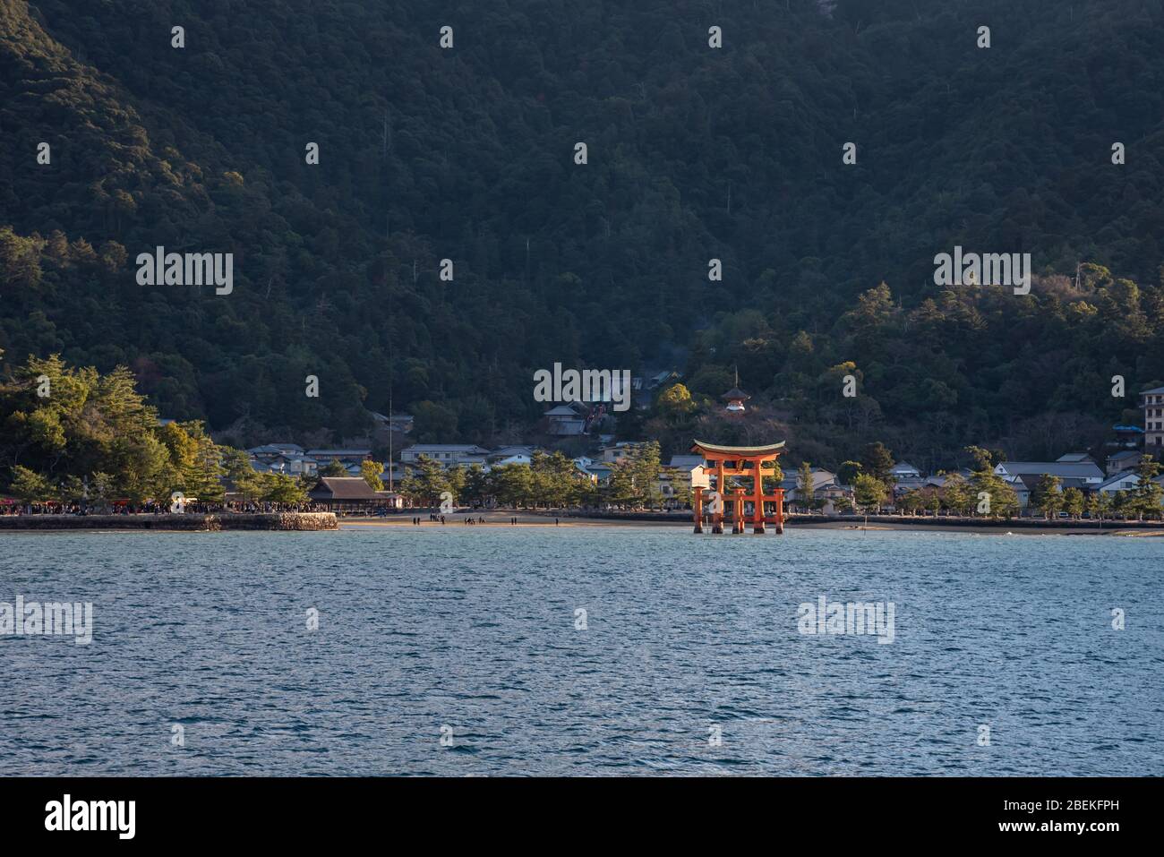 En regardant l'île de Miyajima depuis le ferry. La porte d'embarquement flottante du géant rouge Grand O-Torii se trouve sur la plage de la baie à marée basse le jour ensoleillé, Hiroshima City Banque D'Images
