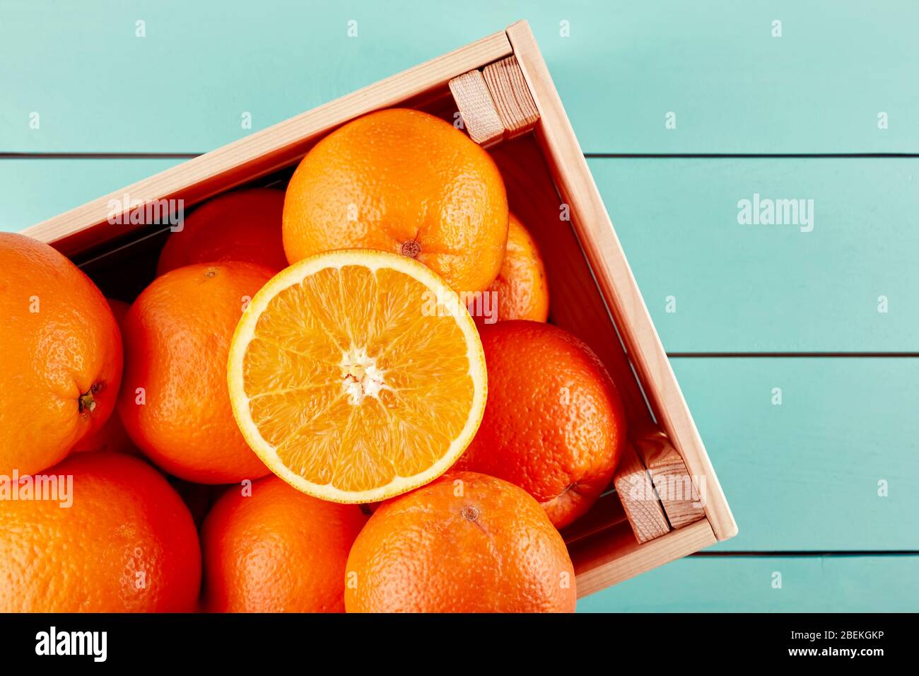 Oranges fraîches dans une boîte en bois ou une caisse sur une table en bois bleu. Vue de dessus. Banque D'Images