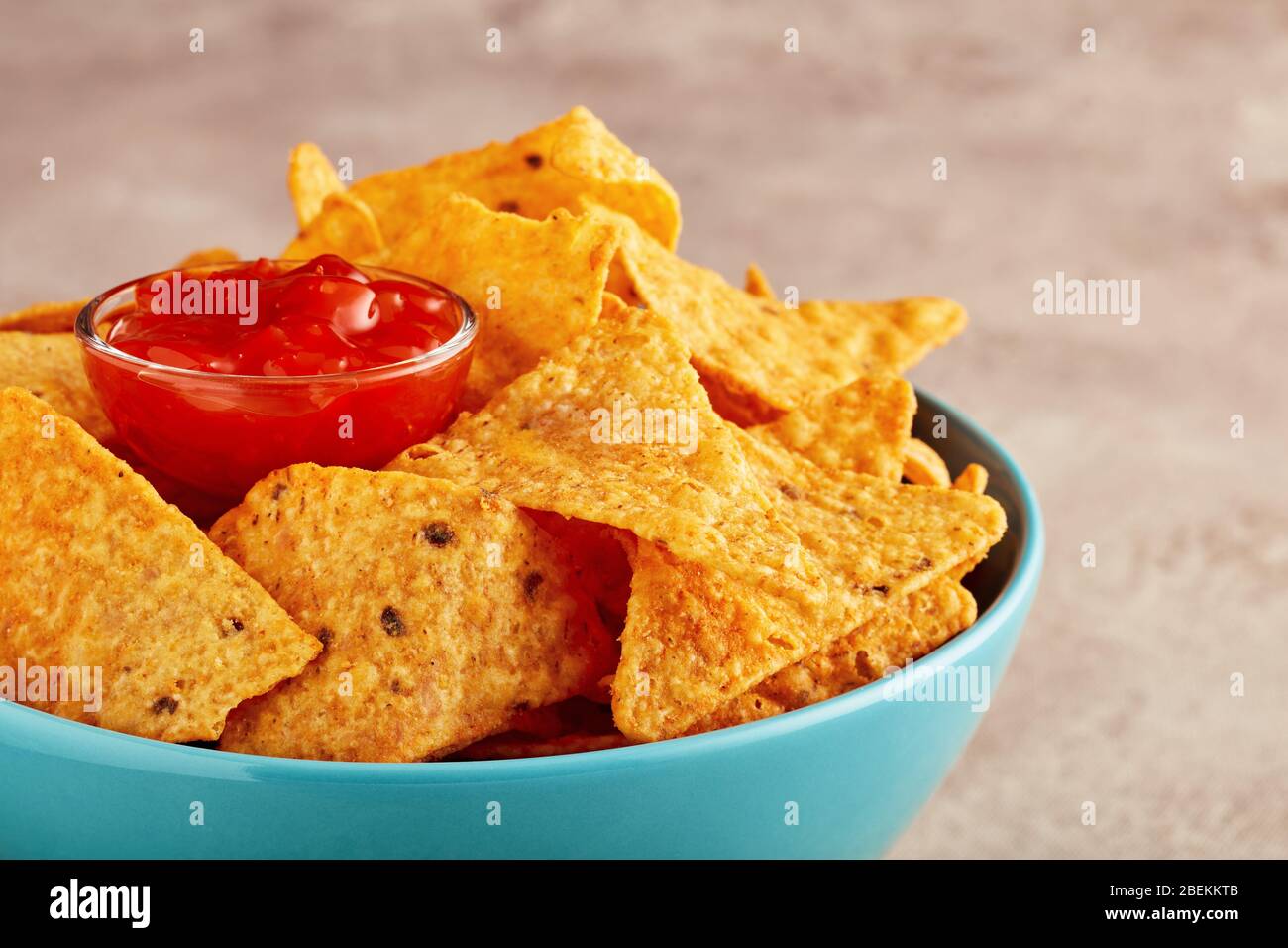 Nachos mexicains ou chips de tortilla dans un bol turquoise avec sauce piquante au piment. Vue rapprochée. Banque D'Images