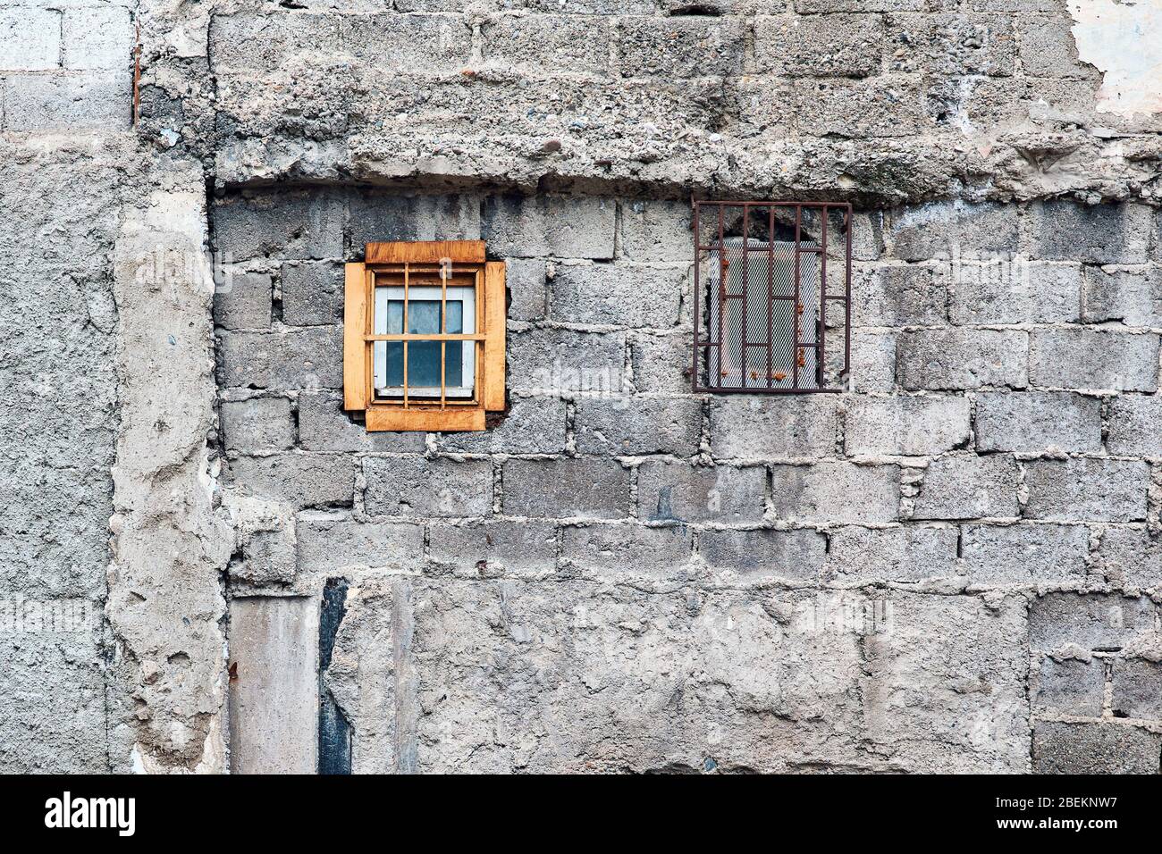 Mur en briques de béton et petites fenêtres d'un ancien bâtiment extérieur abandonné. Banque D'Images