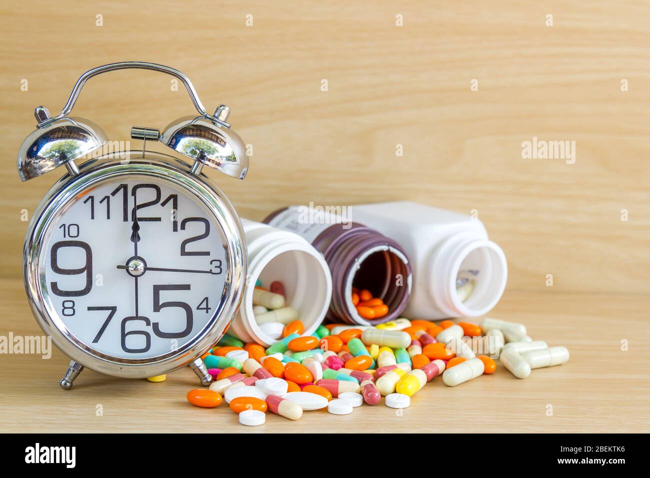 La médecine est comprimé et gélule réveil afficher 12 am ou pm avec copie espace sur table en bois. Banque D'Images