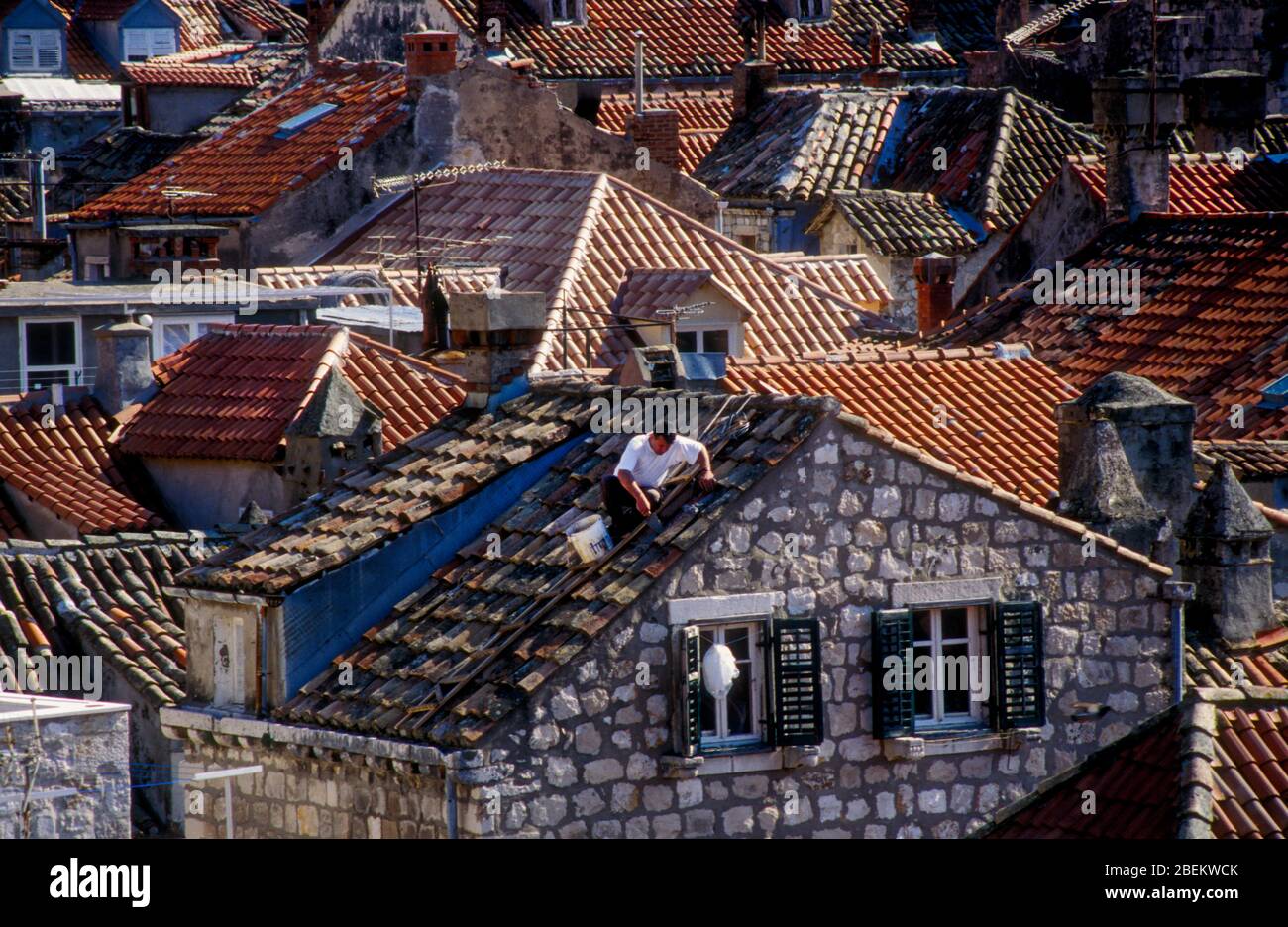 1994 Dubrovnik, Croatie - un homme réparant le toit endommagé par des bombardements dans le centre historique de la ville, photographié lors d'un trêve d'attentats par l'armée serbe Banque D'Images