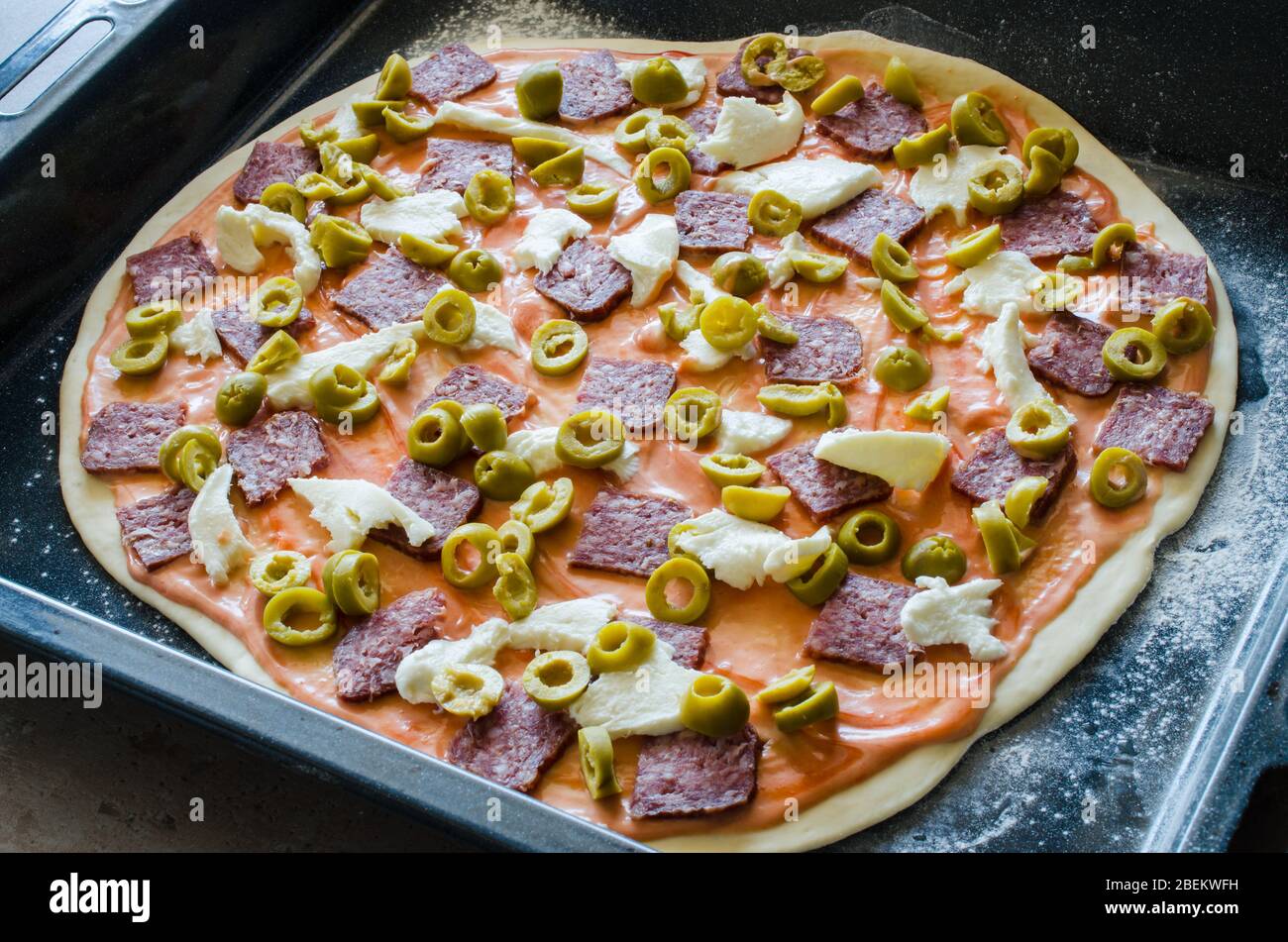 Maison a fait de la pizza crue avec salami, mozzarella, olives et fromage. Gros plan Banque D'Images
