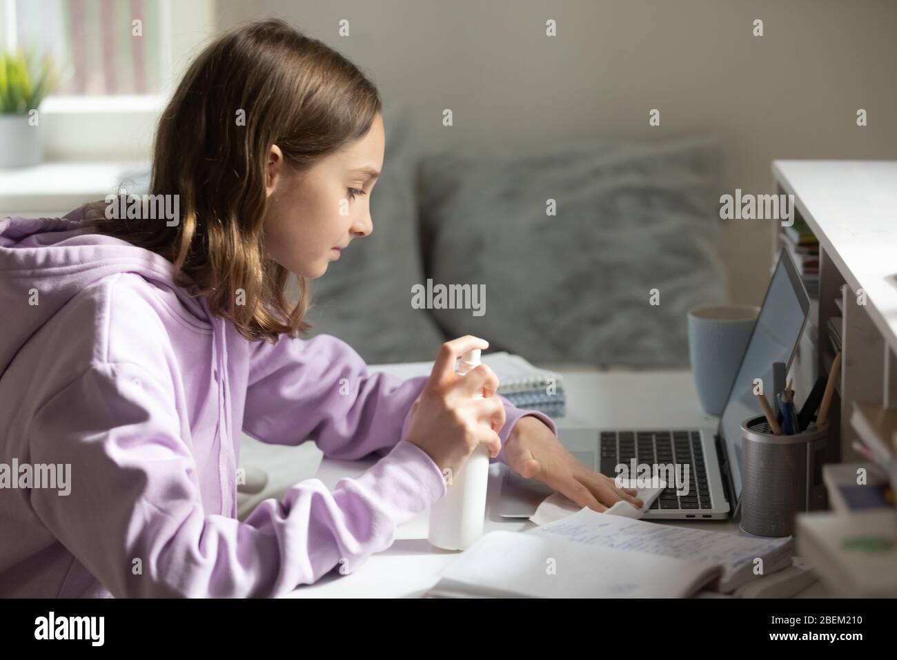 Une adolescente désinfecte son ordinateur avec du gel antibactérien à la maison Banque D'Images