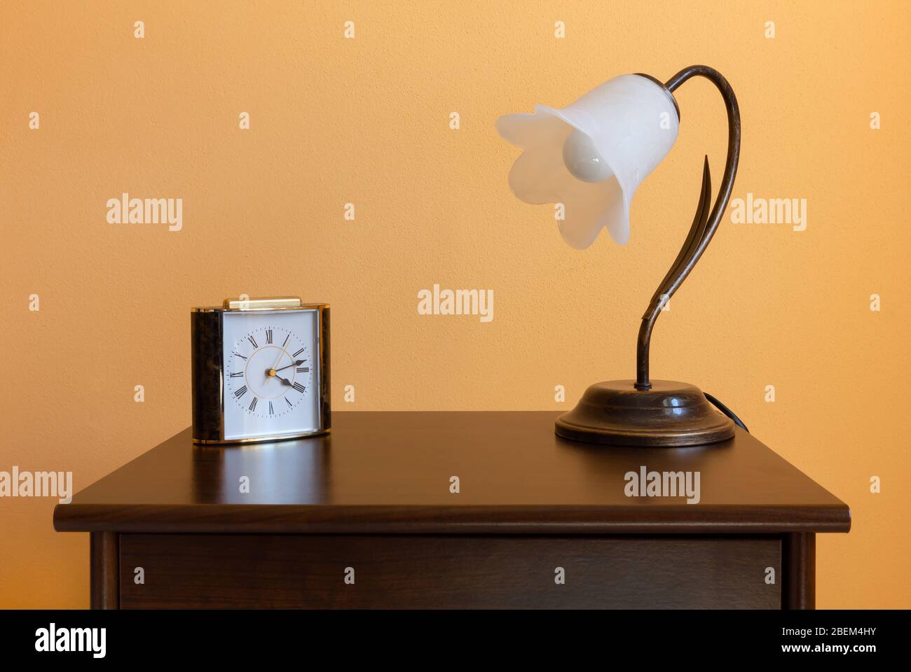 Lampe classique en forme de fleur et réveil sur une table de nuit en bois Banque D'Images