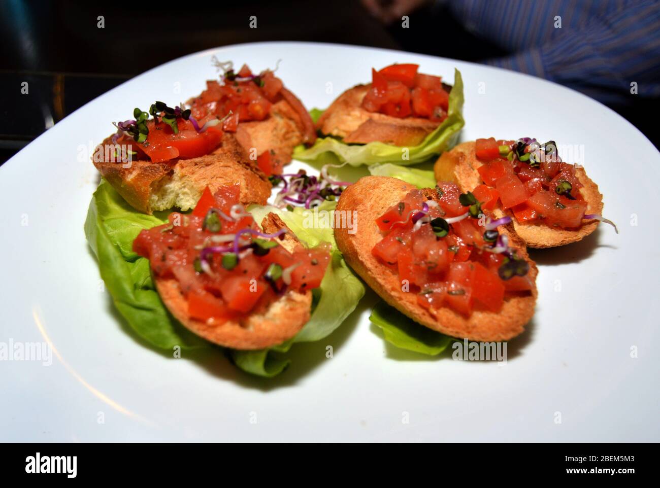 Assiette avec bruschetta mixte sur feuille de laitue verte, placage de la nourriture italienne des doigts, collation saine pour brunch ou apéritif d'Italie, maison faite savoureux o Banque D'Images