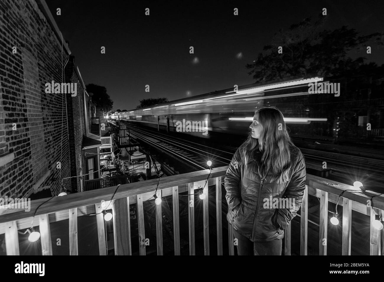 B&W de femme sur sa terrasse en bois dans Lincoln Park comme train va de Banque D'Images
