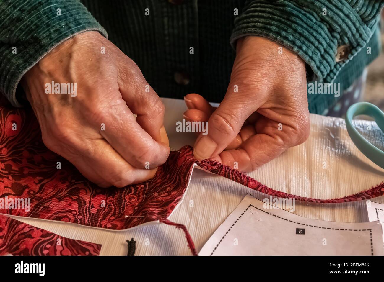 Karen Rentz épinglant un masque en tissu fait maison en préparation à la couture pour préparer à sortir en public pendant la pandémie de Covid-19 dans le micro durement frappé Banque D'Images