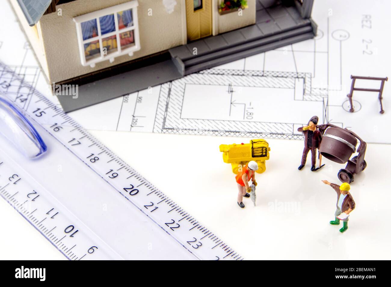 gros plan d'une petite maison en plastique miniature avec des travailleurs de la figurine miniature et des plans de construction Banque D'Images