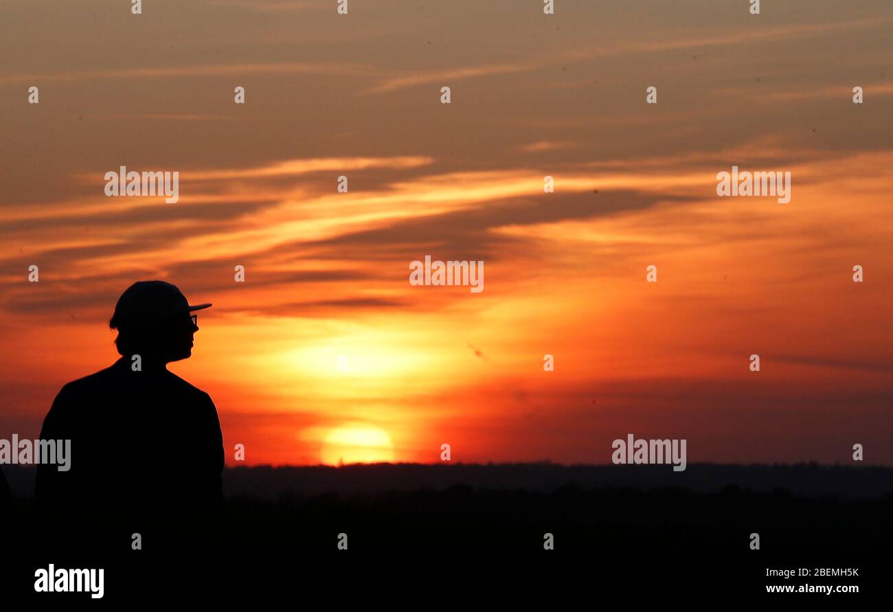 Chesterton, Warwickshire, Royaume-Uni. 14 avril 2020. Météo britannique. Un homme regarde le coucher du soleil depuis le dessous du Moulin Chesterton pendant le verrouillage pandémique du coronavirus. Credit Darren Staples/Alay Live News. Banque D'Images