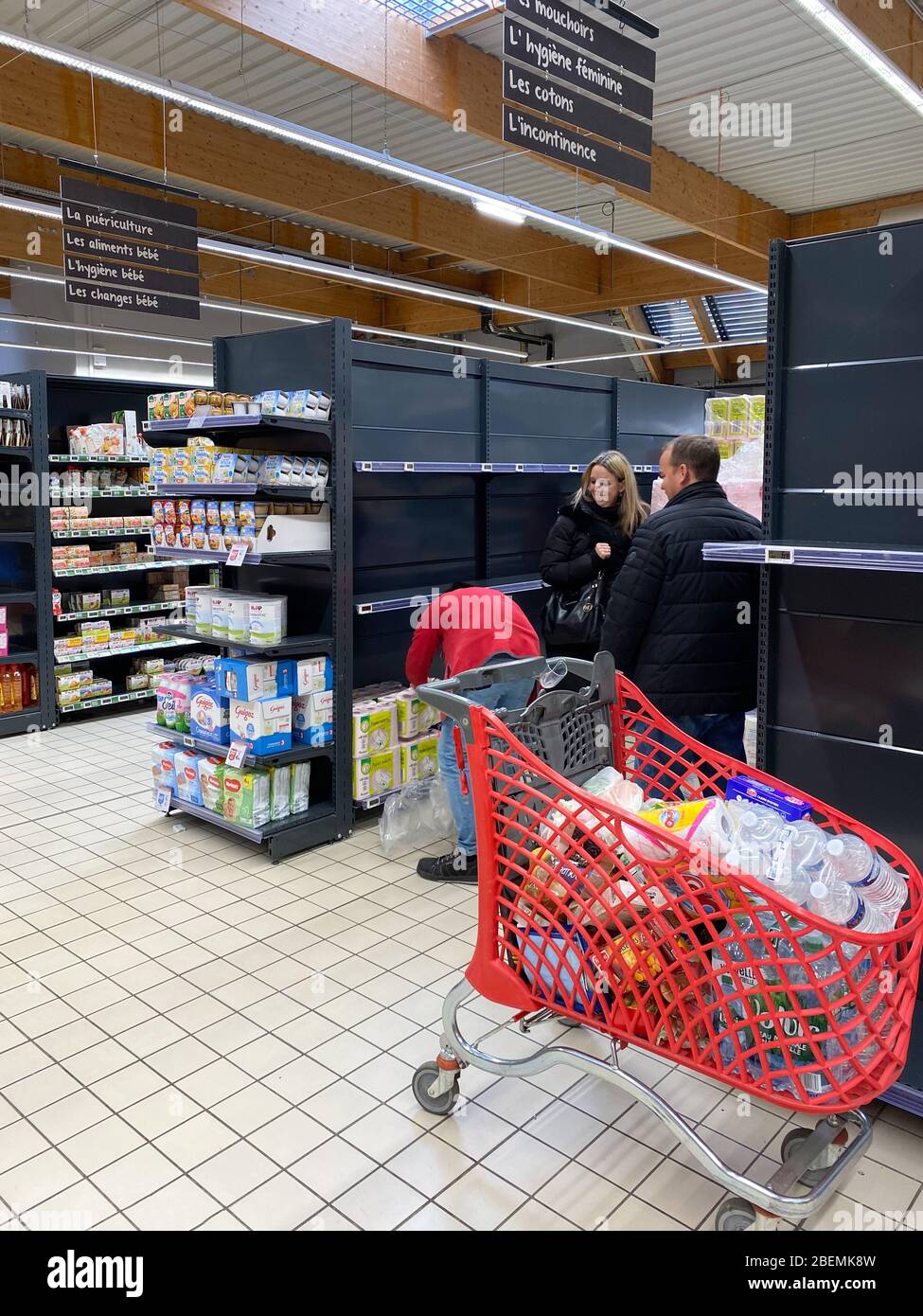 Paris, France - 13 mars 2020: Vue de l'intérieur d'un supermarché français avec des clients près du stand de papier toilette avec des clients faisant des achats pour les derniers rouleaux de papier toilette Auchan pendant la pandémie de Coronavirus Banque D'Images