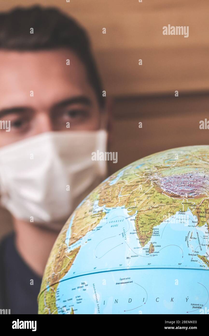 Jeune homme flou voyageur en masque médical regardant le monde entier. Quarantaine du coronavirus. Restrictions de voyage causées par l'éclosion de COVID-19. Voyages et vols annulés. Mise au point sélective. Banque D'Images