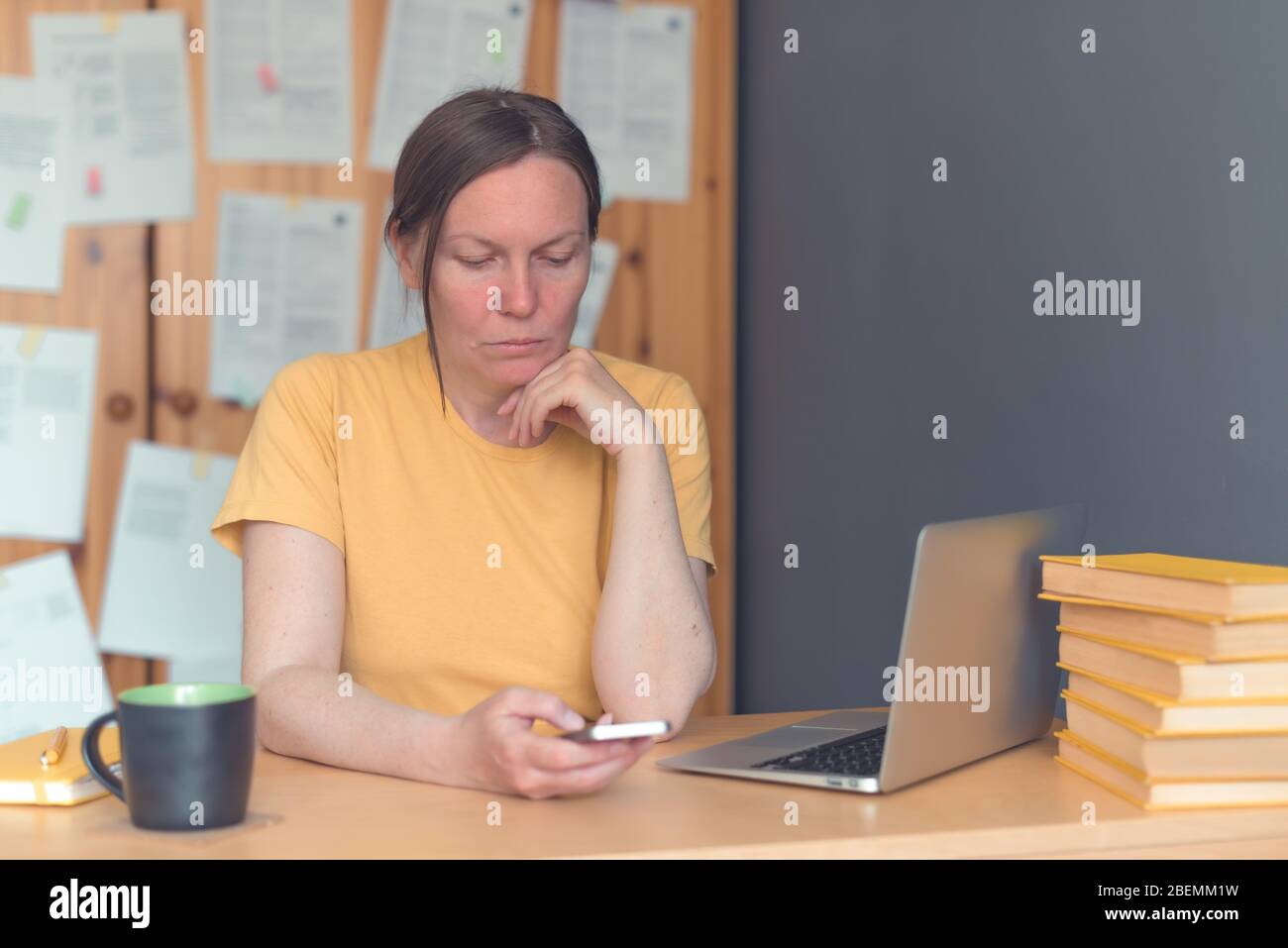 Femme indépendante travaillant sur smartphone au bureau à domicile, en tapant un message texte, mise au point sélective Banque D'Images