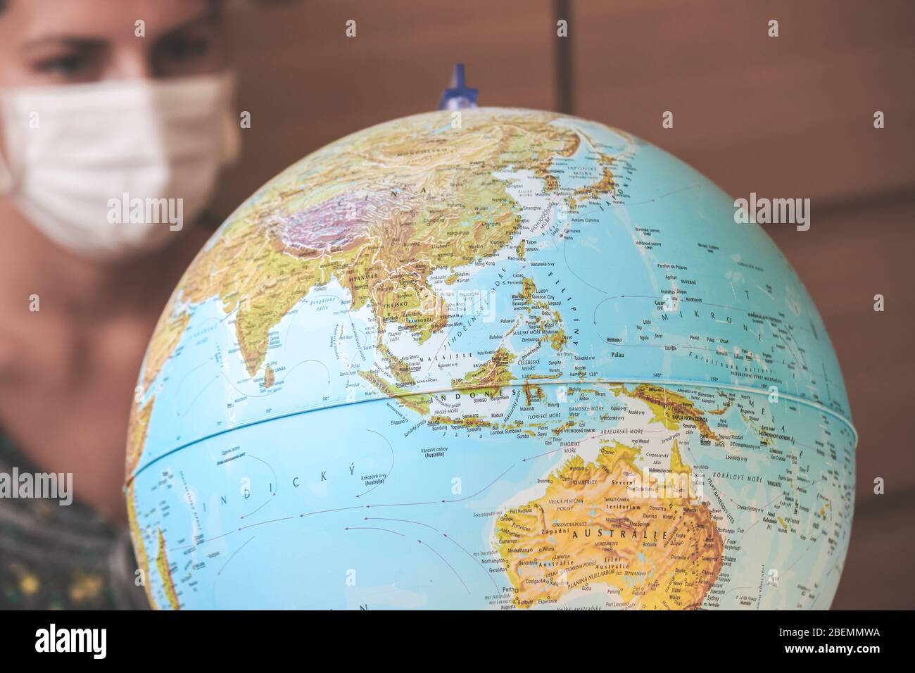 Jeune femme trouble voyageur dans un masque médical regardant le monde entier. Quarantaine du coronavirus. Restrictions de voyage causées par l'éclosion de COVID-19. Voyage annulé. Mise au point sélective. Banque D'Images