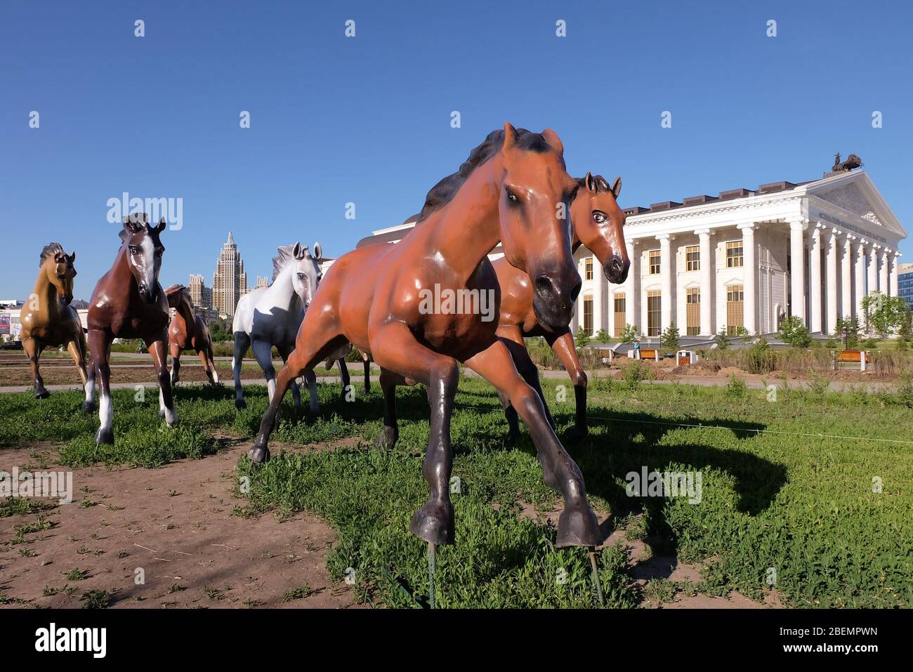 NUR-SULTAN, ASTANA, KAZAKHSTAN - 3 JUIN 2015 : des monuments de sept chevaux de couleur brune et blanche sont en train de courir devant un blanc nouvellement construit Banque D'Images