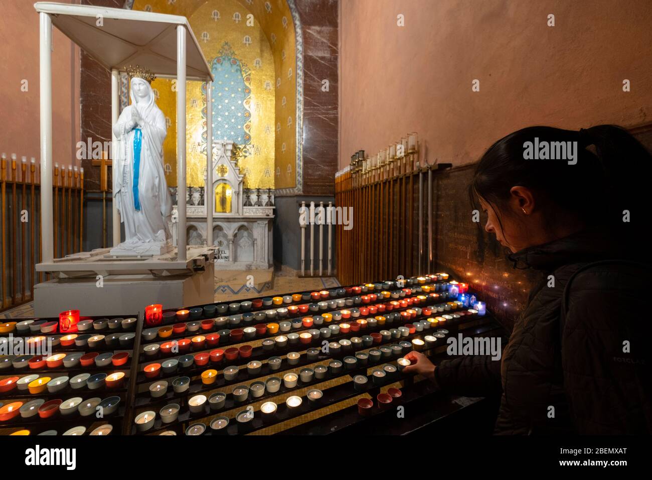 Femme priant à la statue de la Vierge Marie après avoir illuminé une bougie à la basilique notre-Dame du Rosaire dans le Sanctuaire De Notre-Dame de Lourdes, France Banque D'Images