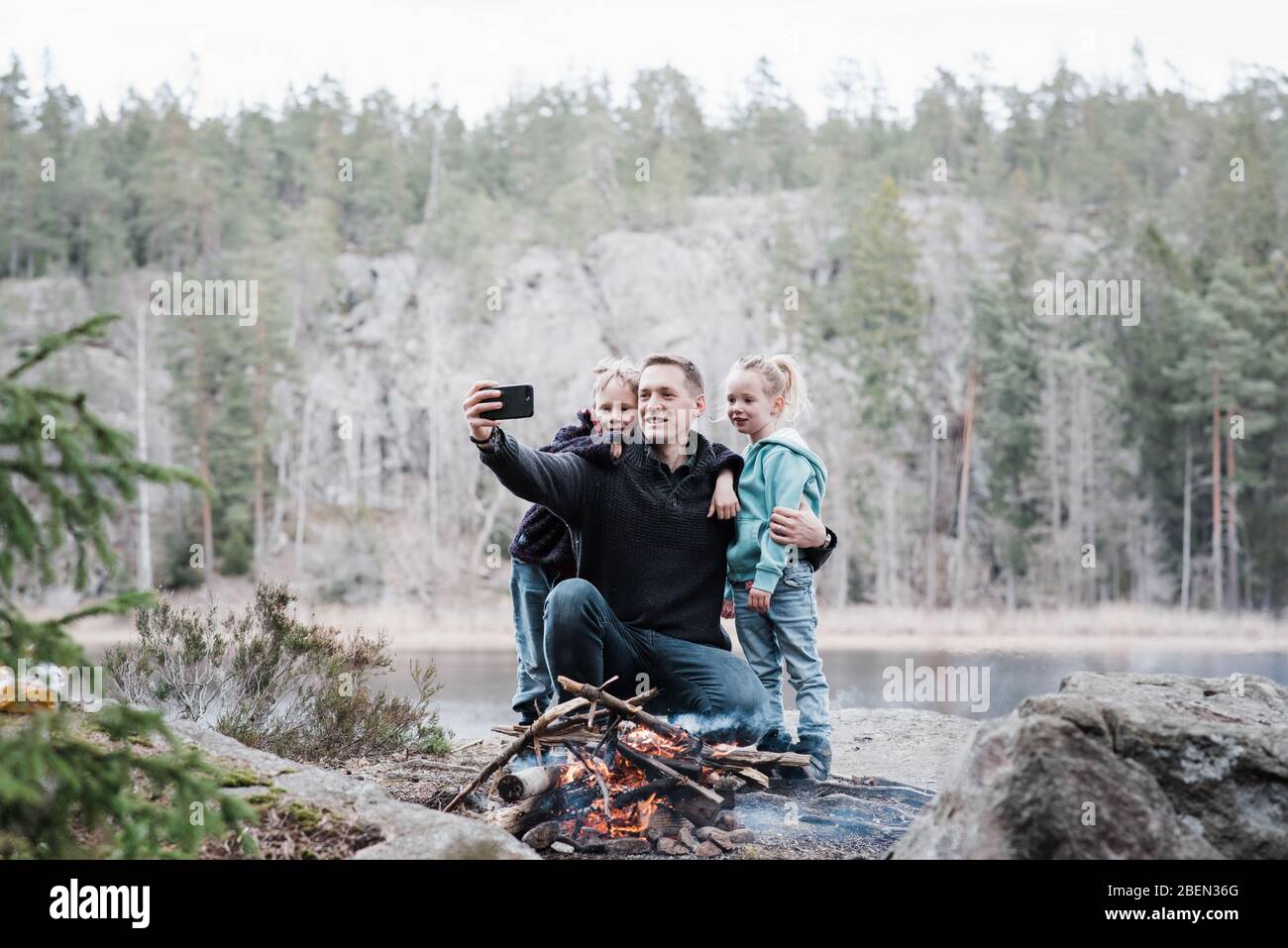 père prenant des photos avec ses enfants tout en appréciant un feu de camp Banque D'Images