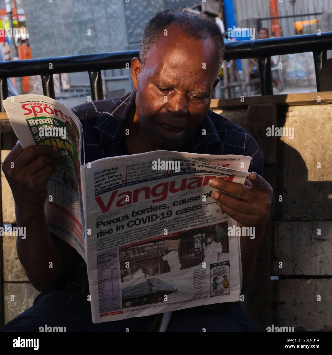 Un homme lit un journal avec un titre sur Covid-19 pendant le verrouillage à Lagos, au Nigeria. 3 avril 2020. Crédit: Adeyinka Yusuf Banque D'Images
