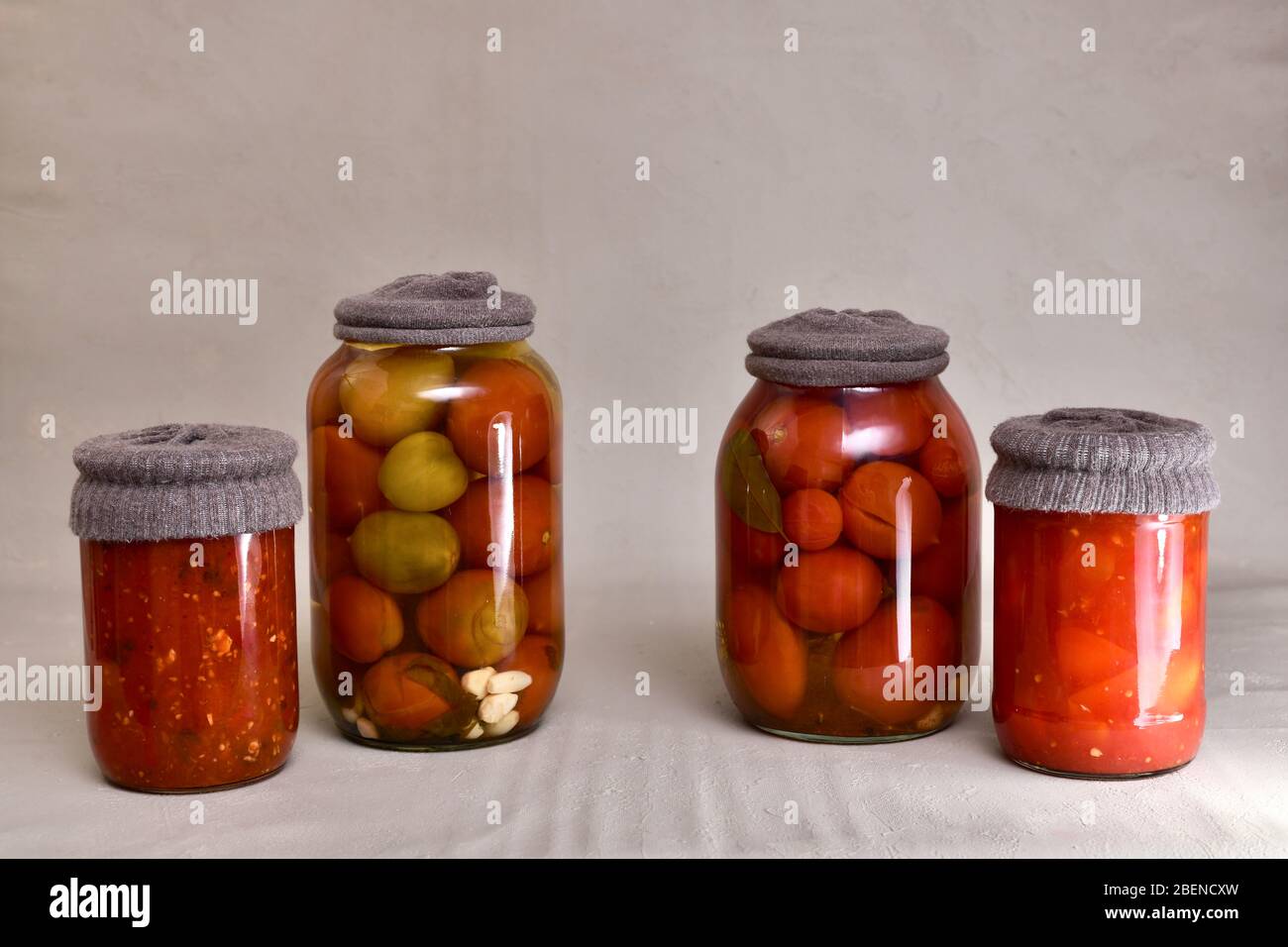 Quatre pots en verre, avec bouchons en matières textiles contre la rouille, avec tomates fermentées, poivrons, aubergines. Banque D'Images